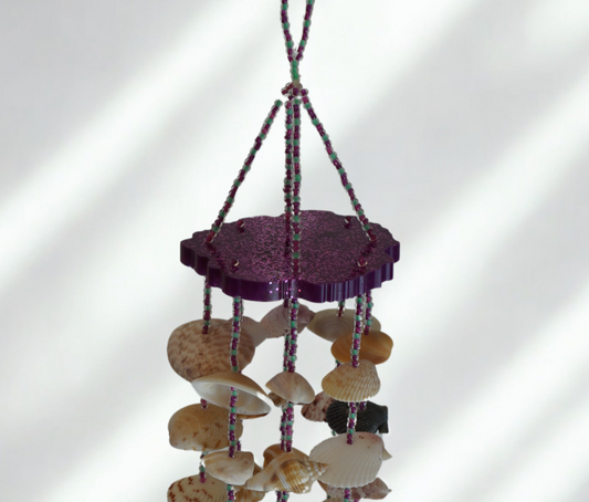 Decorative shell chime with purple base and shell components on a white background