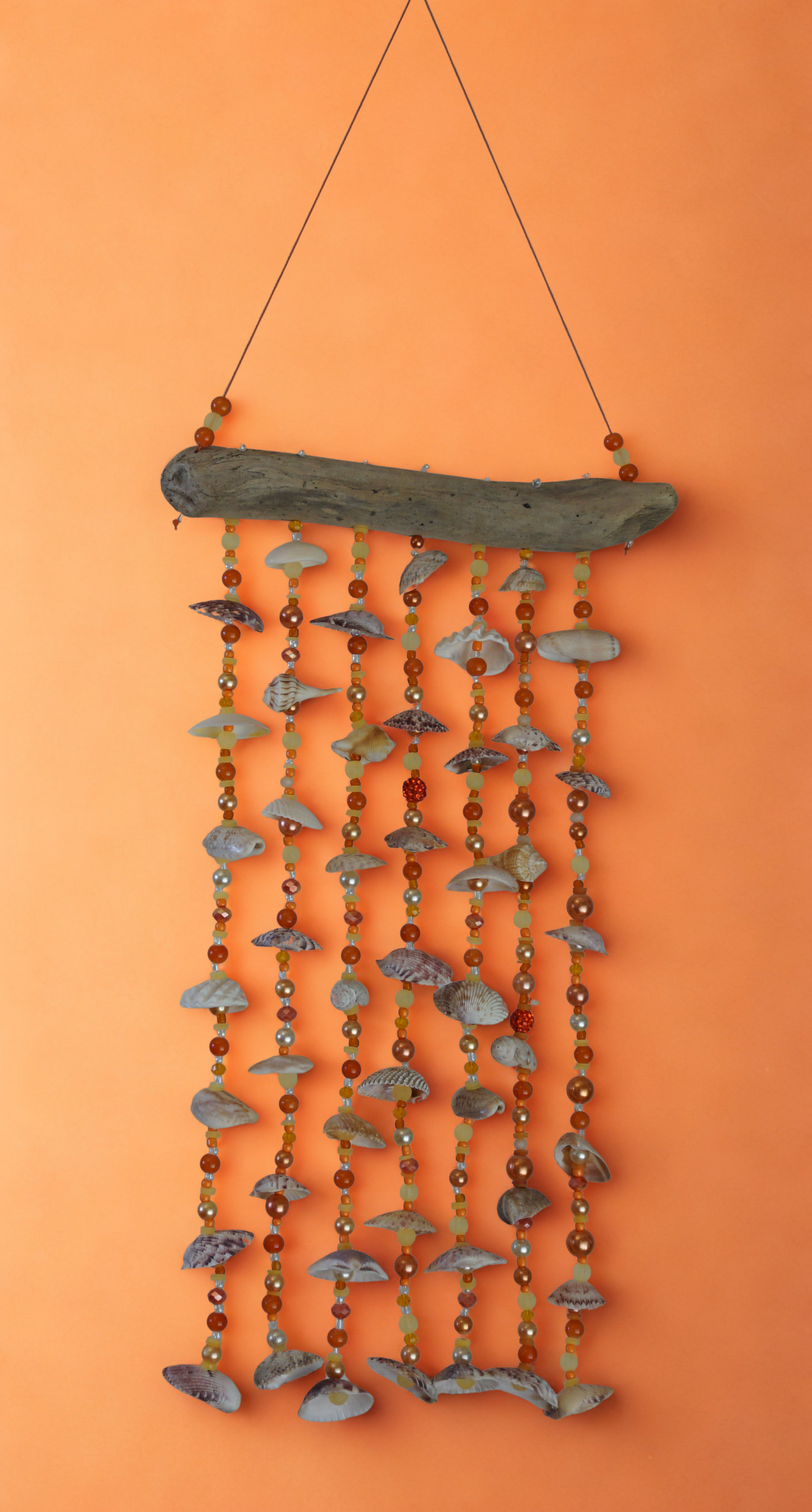Decorative wall hanging with shells and beads on an orange background