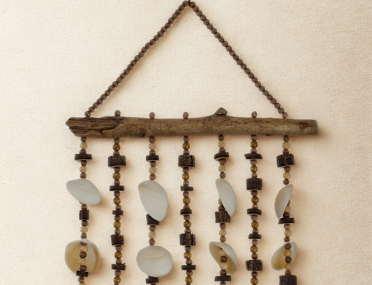 Decorative wall hanging with beads, natural wood elements and shells on a beige background