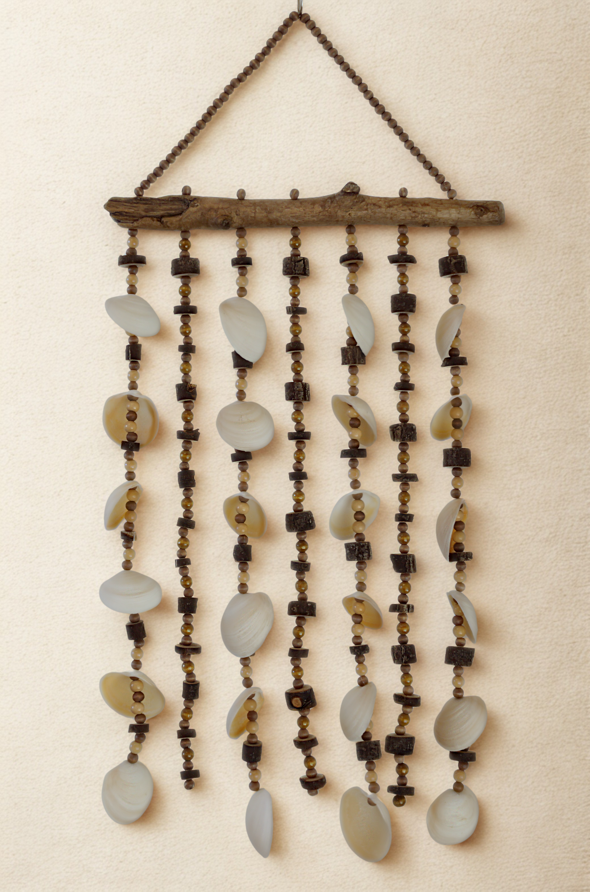 Decorative wall hanging with shells, beads, wood on a beige background