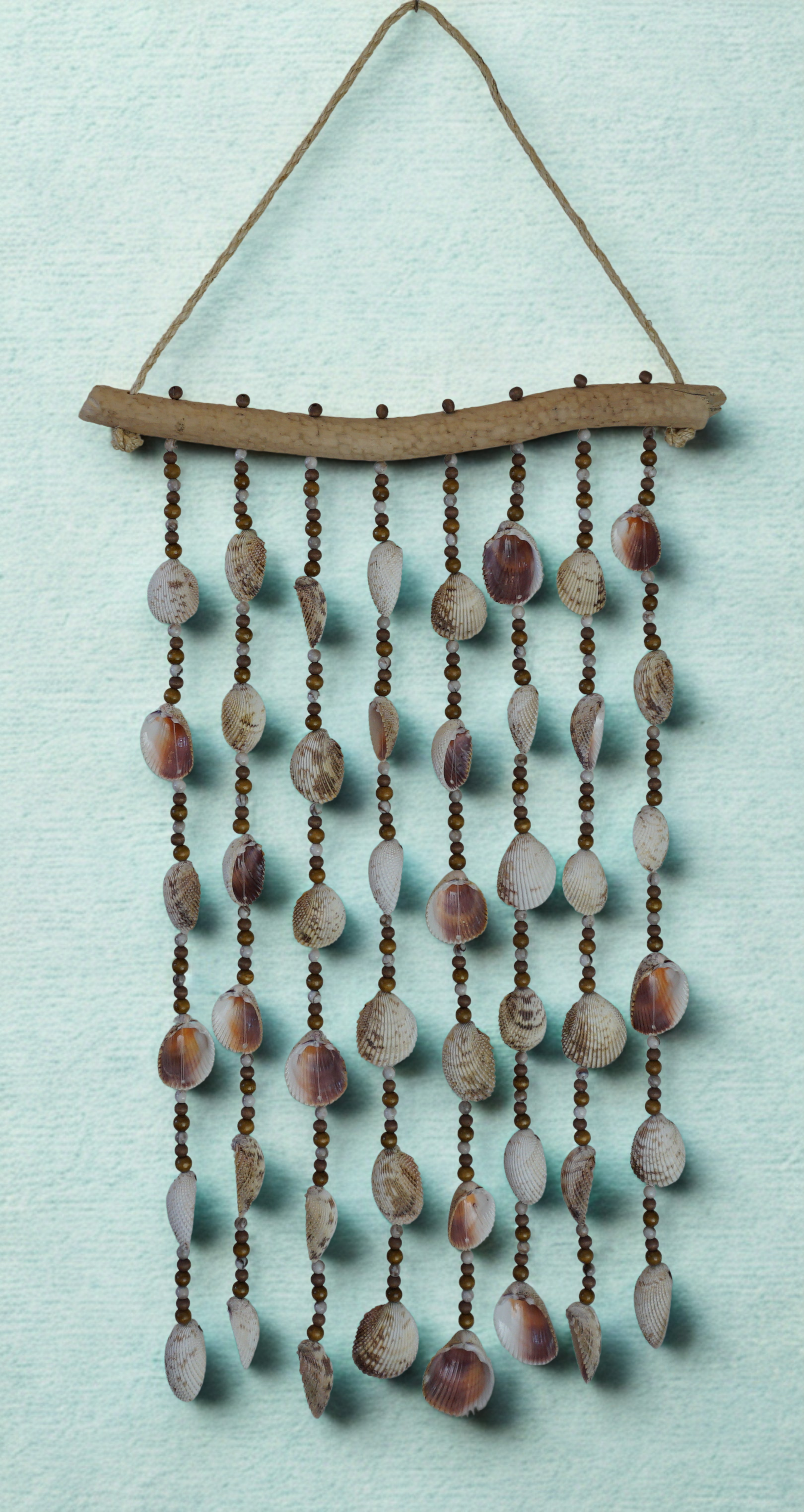 Decorative wall hanging with shells and beads on a light blue background