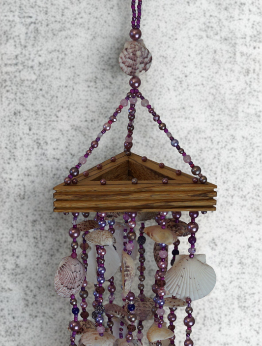 Decorative wind chime with seashells and beads on a textured surface