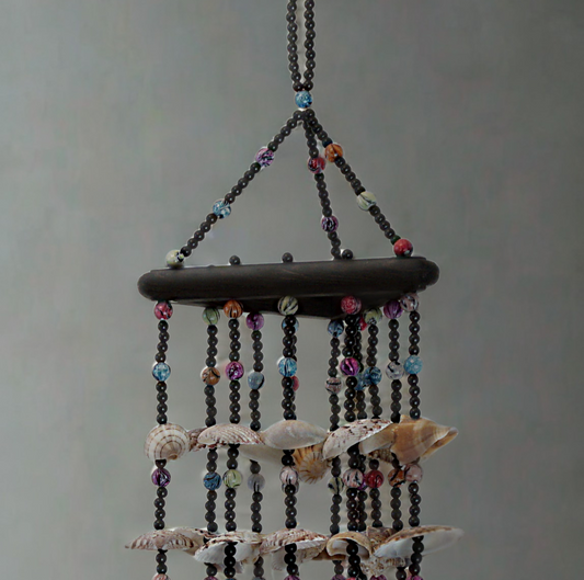 Decorative hanging wind chime with shells and beads on a plain background