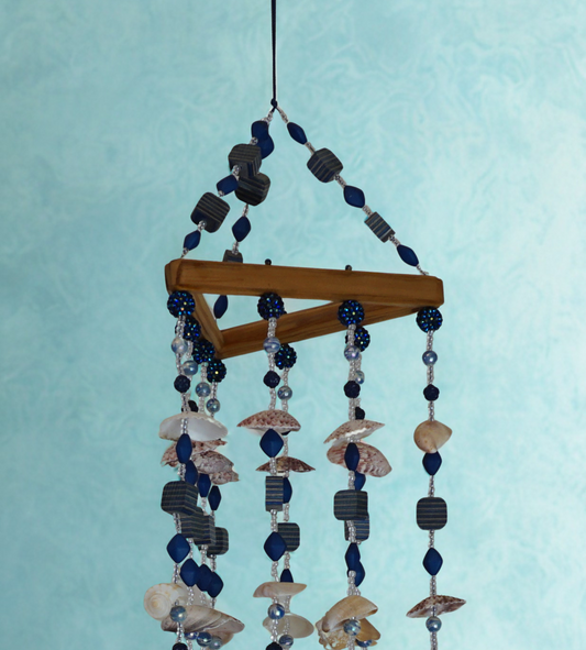 Decorative wind chime with seashells and beads on a light blue background