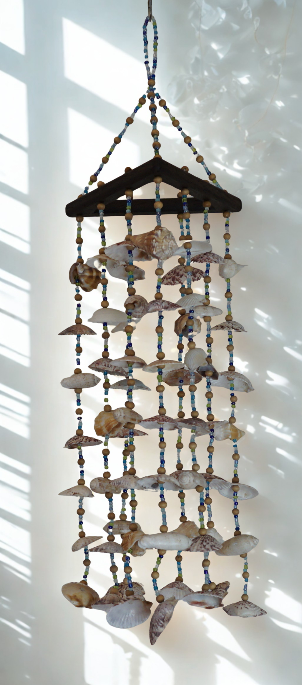 Decorative hanging wind chime made of seashells and beads on a white background