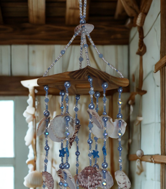 Decorative shell and bead wind chime hanging in front of a wall