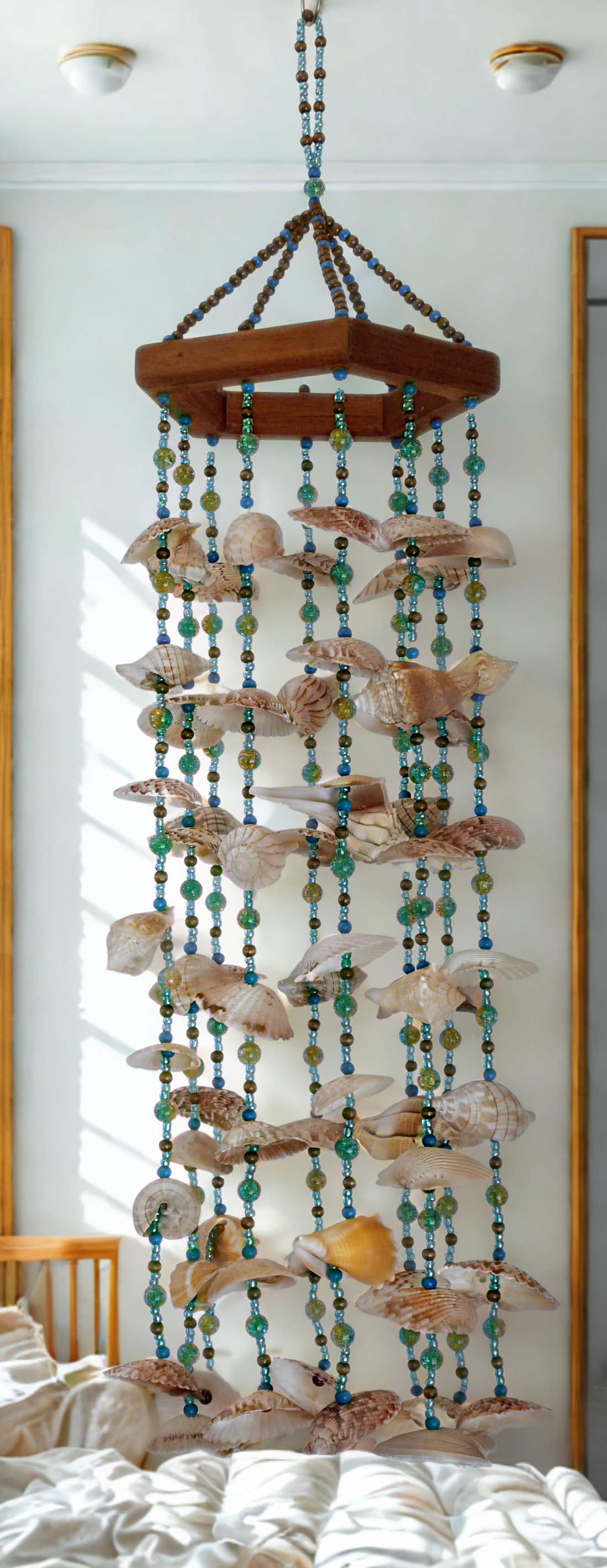 Decorative shell and bead hanging wind chime on a white wall.