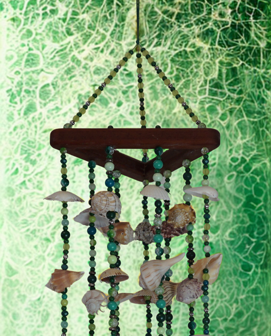 Decorative wind chime with seashells and beads against a green textured background
