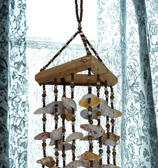 Shell wind chime hanging against a textured white background